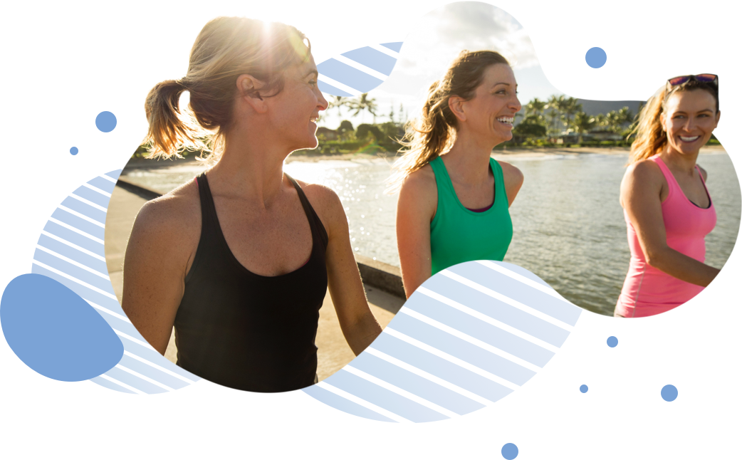 Three women walking together and smiling with a lake in the background